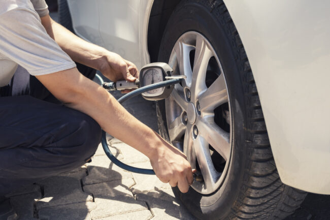 mężczyzna sprawdzający ciśnienie w oponach